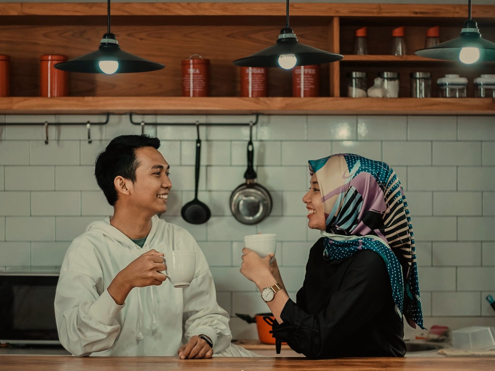 A couple laughing over coffee in their kitchen